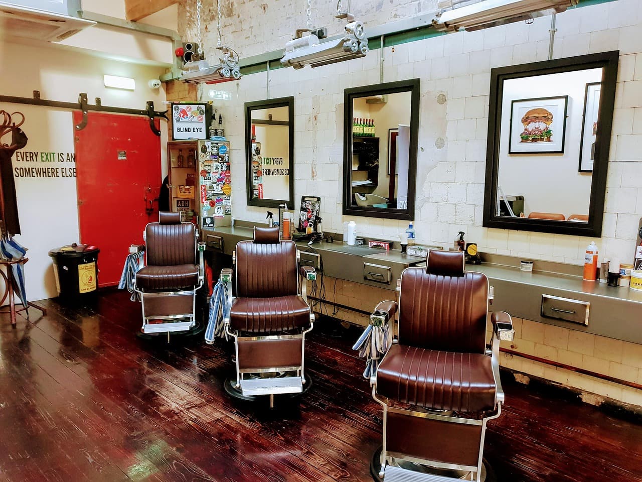 A row of leather barber chairs and mirrors in a bright shop
