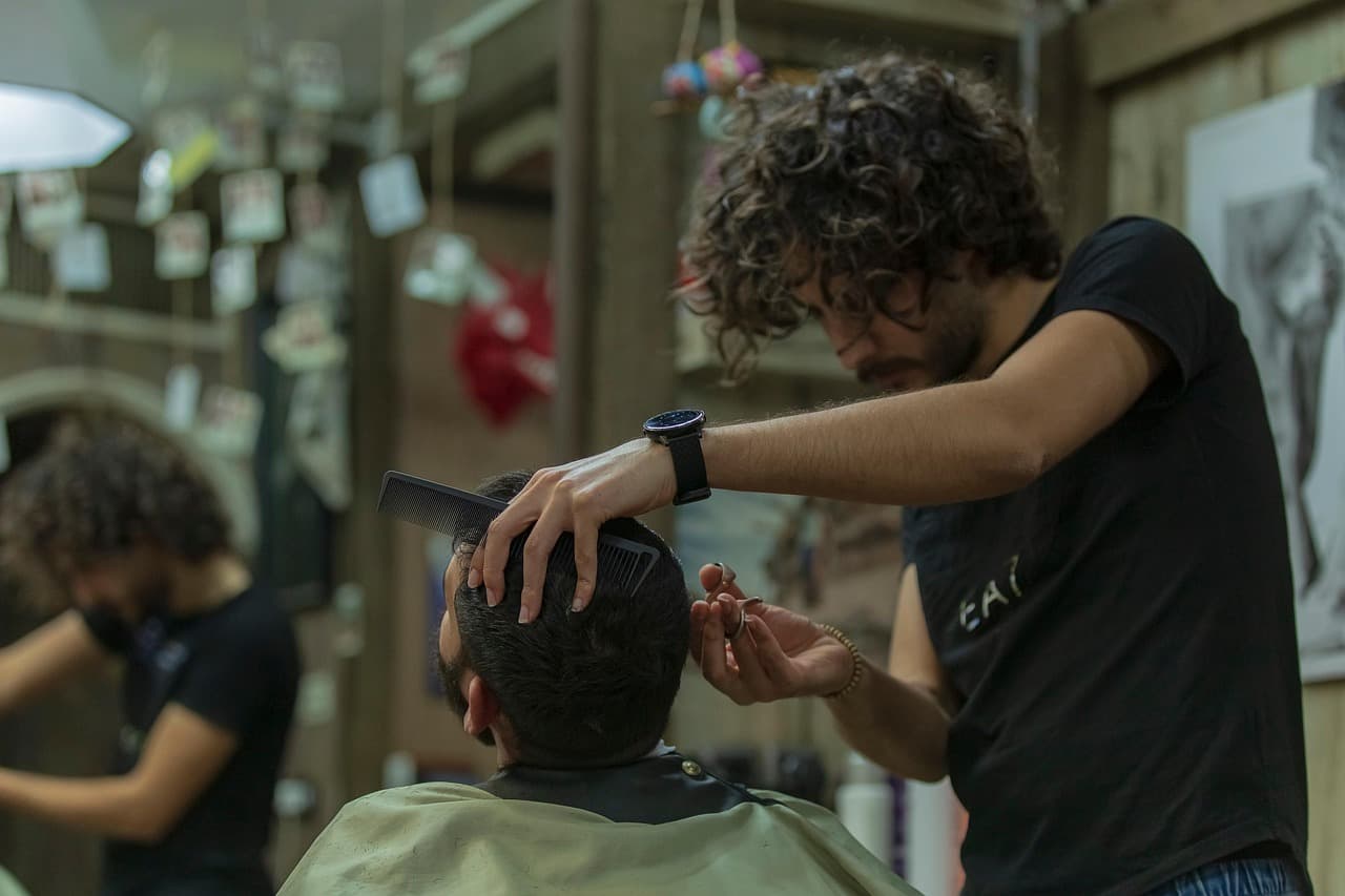 A barber combing and cutting a customer’s hair under the cape
