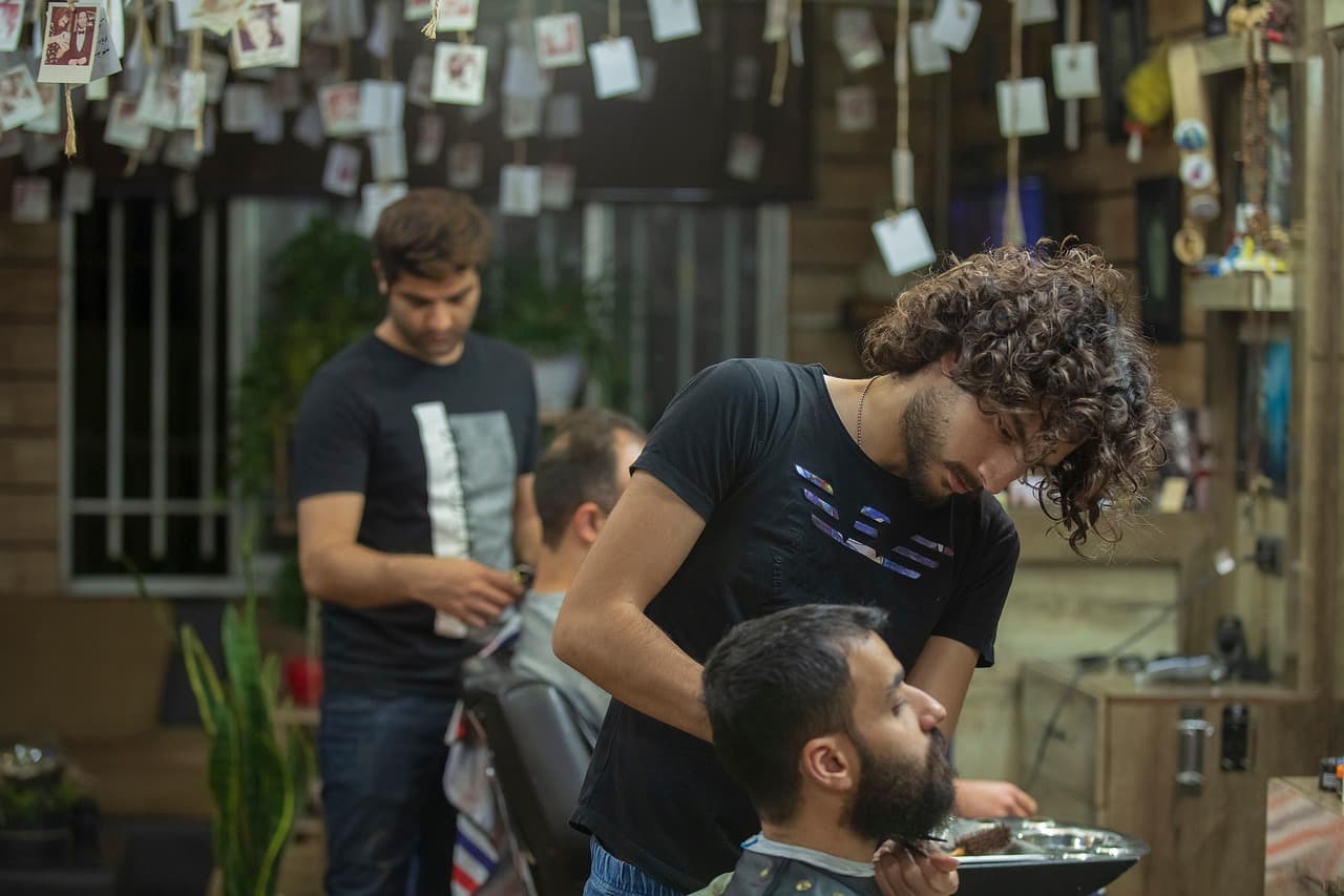 Two barbers at work on a customer’s cut and beard